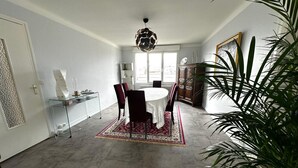 A dining area with a round table, chairs, a chandelier, and a large plant. - T3 city centre- elevator- parking- panoramic view (Châteauroux)