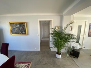A room with a large painting, a potted plant, and a staircase leading to another area. - T3 city centre- elevator- parking- panoramic view (Châteauroux)