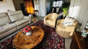 A living room with a sofa, two armchairs, a coffee table with a rug, and a view into the dining area. - T3 city centre- elevator- parking- panoramic view (Châteauroux)