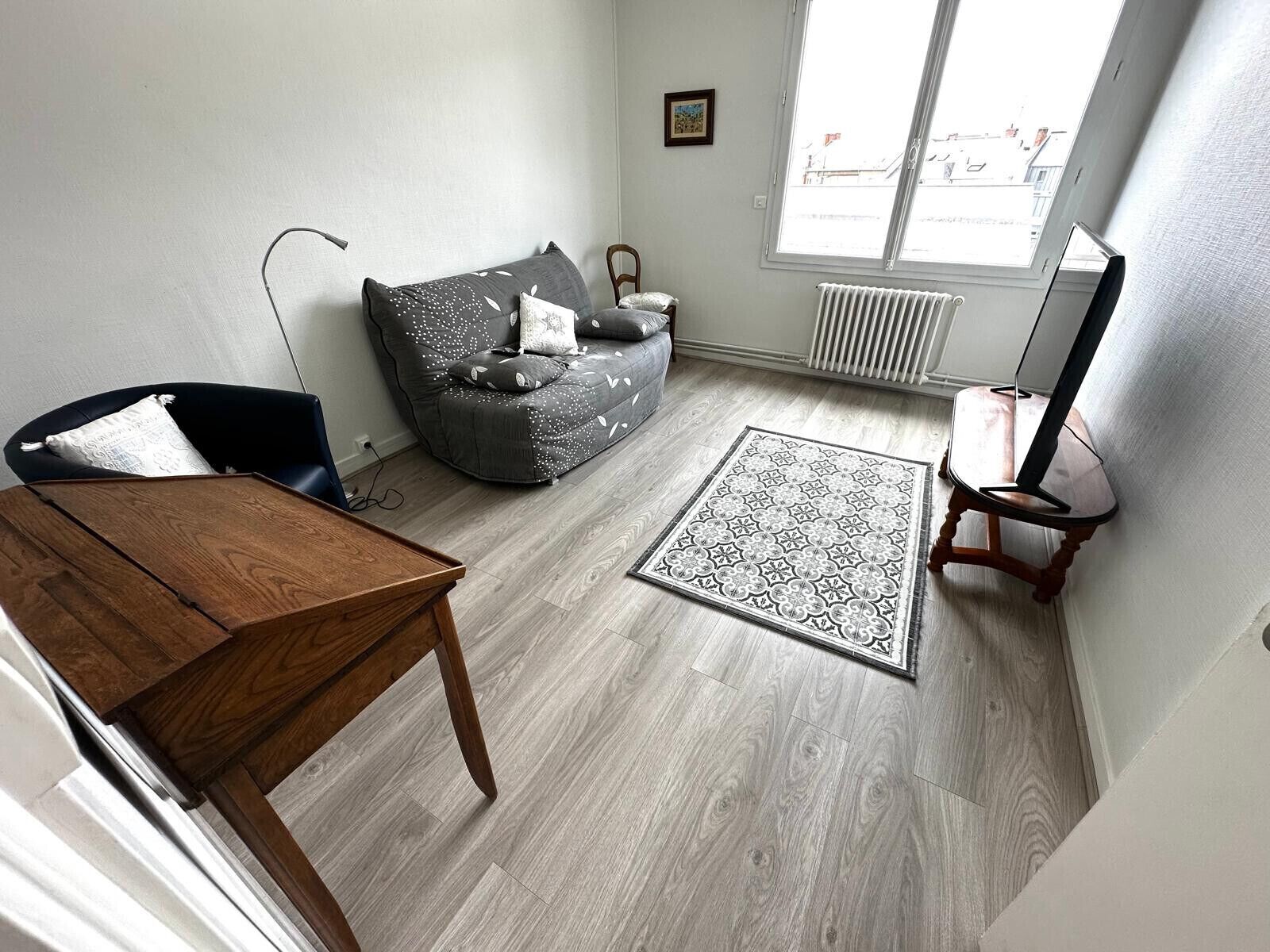 A living room with a sofa, a wooden table, a patterned rug, and a television.