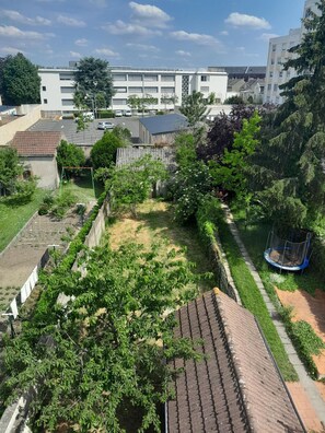 Ein Wohngebiet mit Garten, Trampolin und einem Gebäude mit vielen Fenstern im Hintergrund.