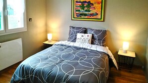 Ein Schlafzimmer mit einem Bett, zwei Nachttischen, einem Fenster und einem Wandbild.