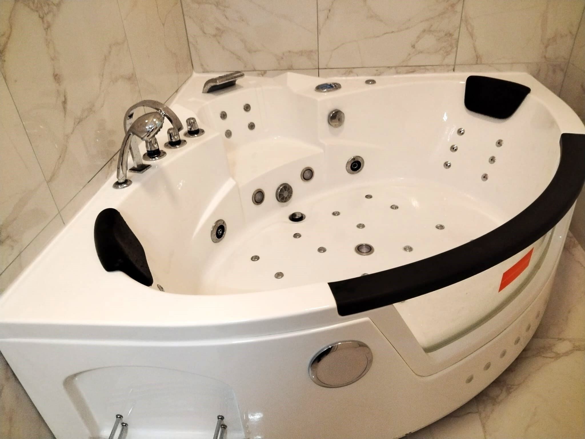 Un jacuzzi moderne doté de plusieurs jets, d’un panneau de commande et d’un siège intégré.