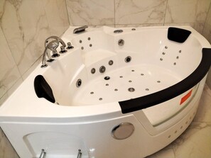Ein modernes Whirlbad mit mehreren Düsen, einer Steuerung und einer integrierten Sitzgelegenheit.
