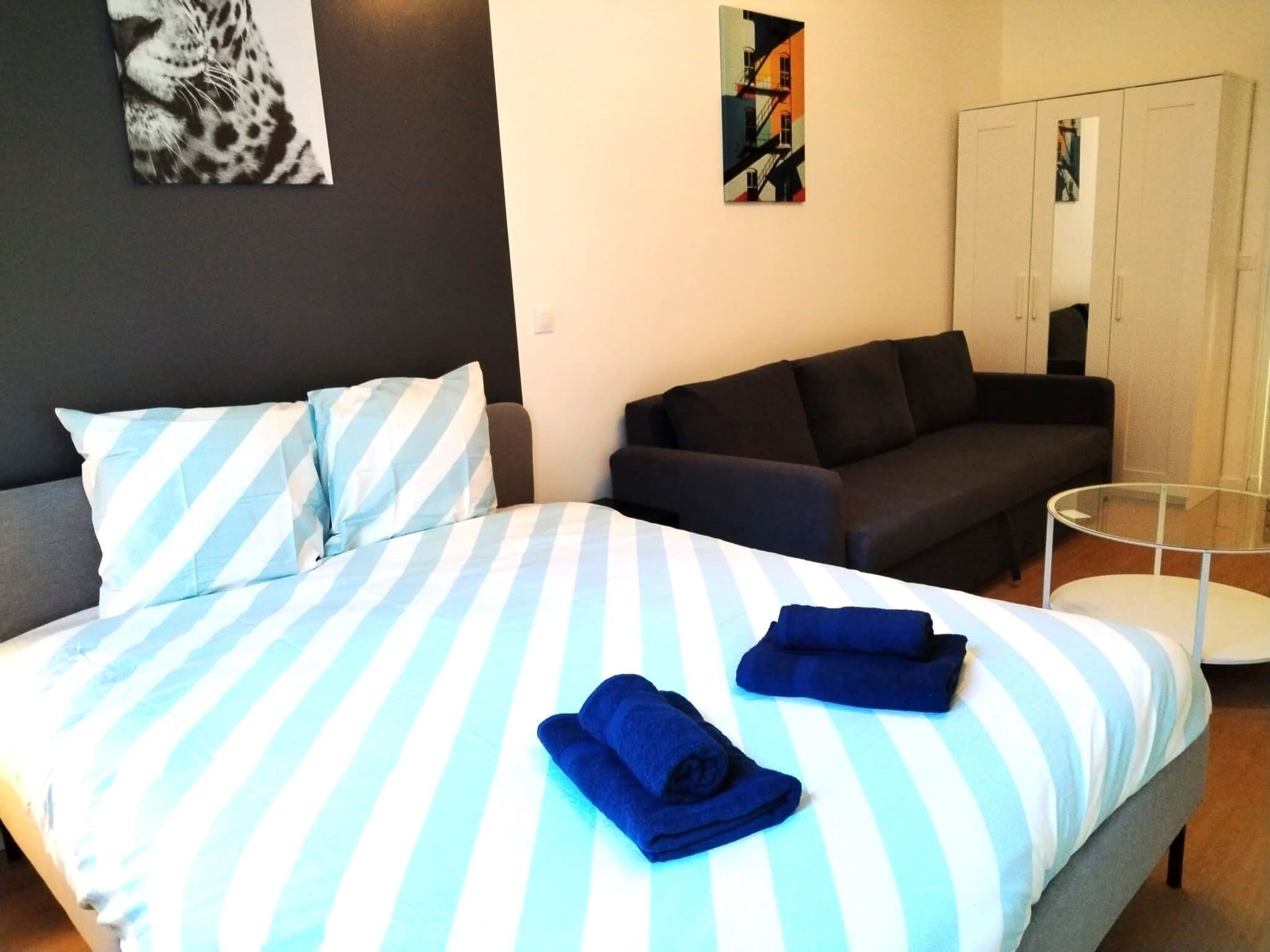 Une chambre d’hôtel avec un lit, un canapé, une petite table ronde et une armoire.