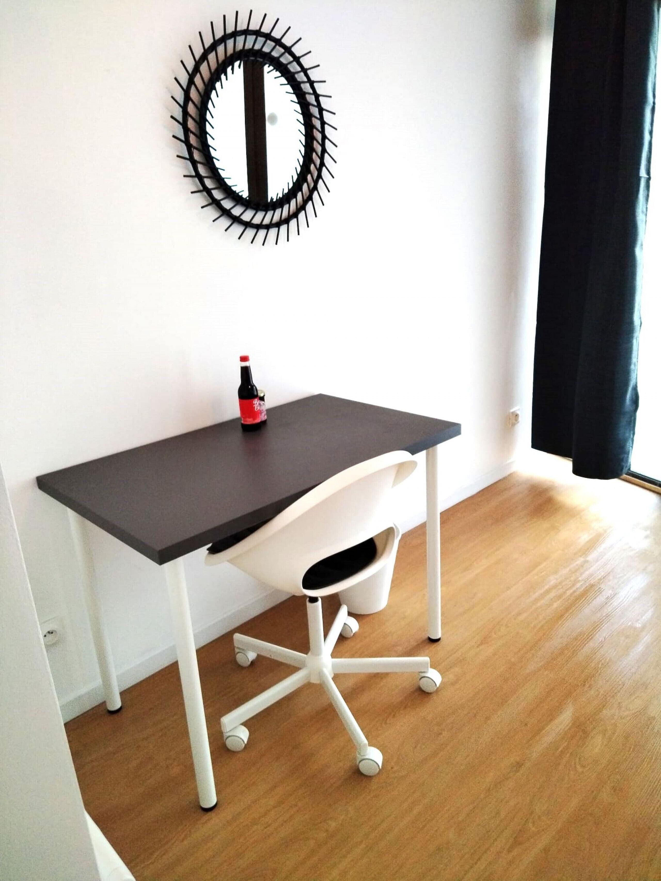 A modern office space with a desk, chair, and a decorative mirror on the wall.