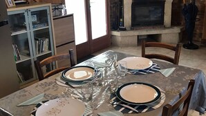 Un comedor con una mesa preparada para cuatro, chimenea y televisor montado en la pared.