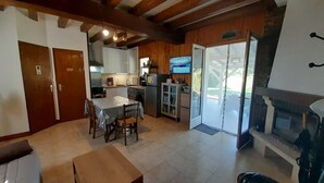 Cocina compacta con comedor, televisor y puerta corrediza de vidrio a un patio exterior.