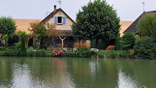 Una casa con jardín y estanque al frente.