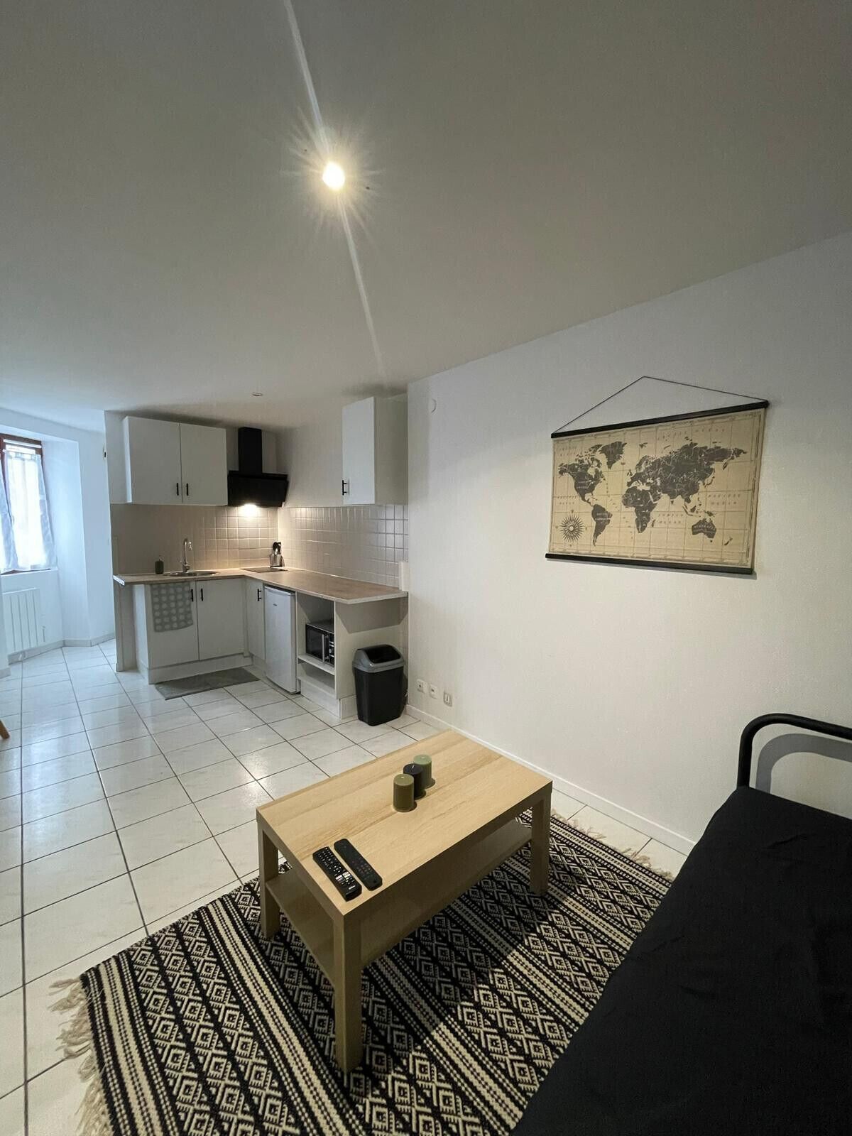 Un espace de vie compact comprenant un coin cuisine, une table basse et un tapis à motifs.