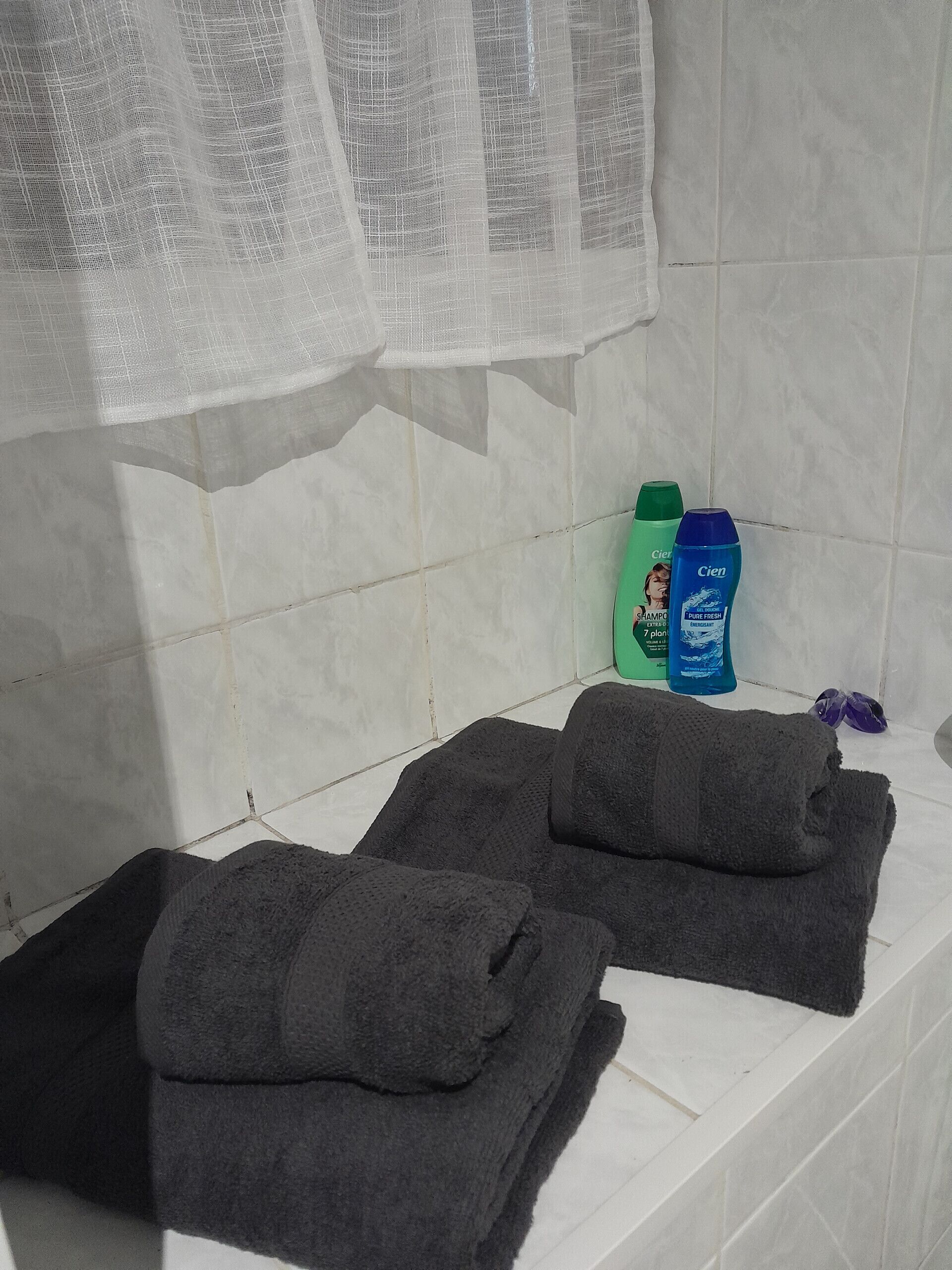Une salle de bain avec une baignoire, deux serviettes et deux bouteilles de shampoing.