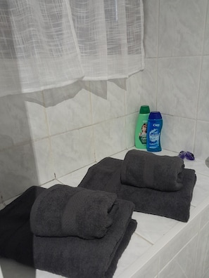 A bathroom with a bathtub, two towels, and two bottles of shampoo.