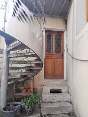 A spiral staircase with metal railings and potted plants.