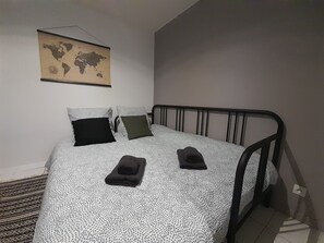 A single bed with a patterned bedspread, two pillows, and a world map on the wall.