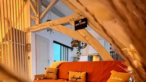 Ein gemütliches Zimmer mit einer Holzbänkchen-Couch, einem hängenden Schild mit einem WLAN-Code und einem großen Fenster.