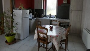 A kitchen with a dining table, chairs, a refrigerator, and a window.