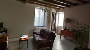 A living room with a sofa, a small table, a lamp, a television, and a potted plant.