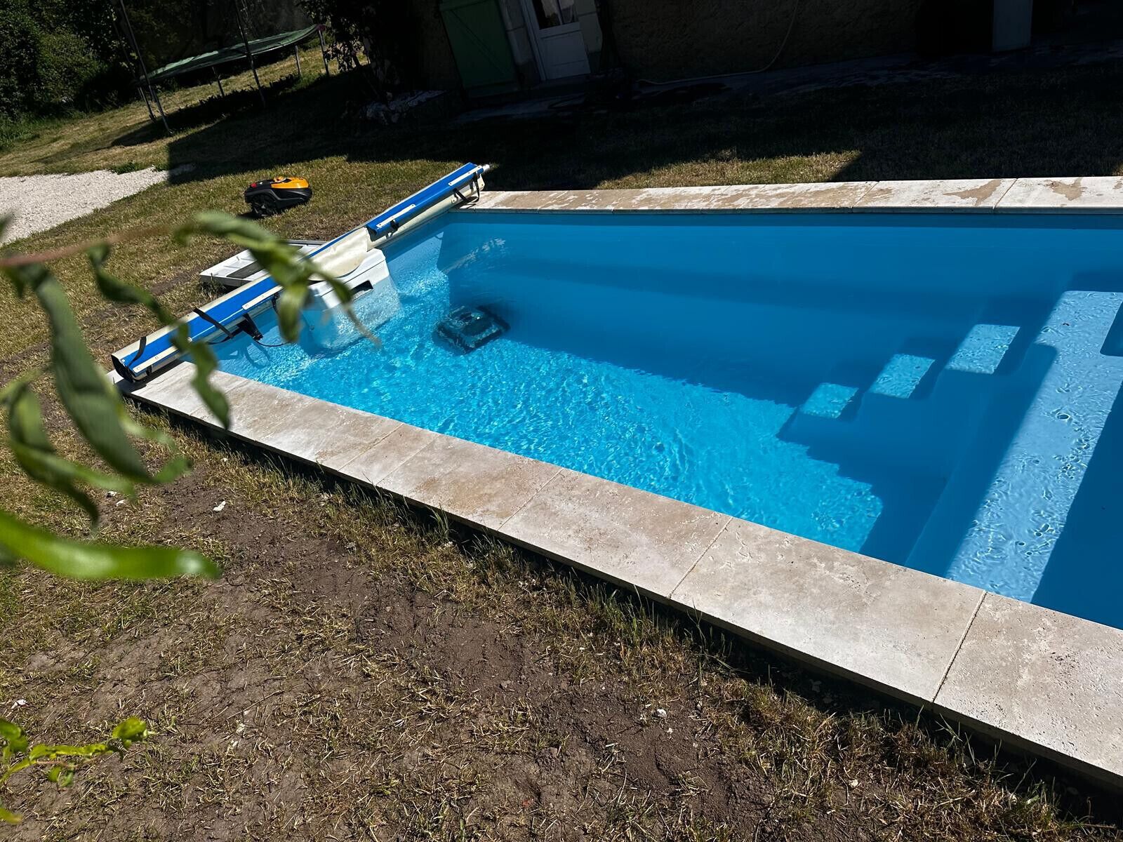 A rectangular swimming pool with a tiled edge, a ladder, and a floating object.