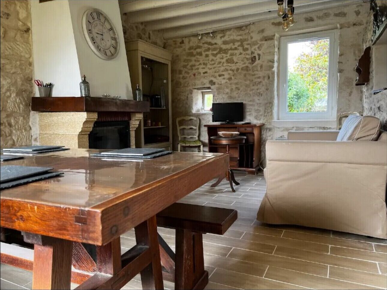 Une pièce rustique avec une table en bois, un canapé, une télévision et un mur en pierre.