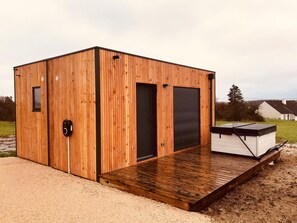 Una cabaña de madera con una puerta, un ventanal y una pequeña terraza.