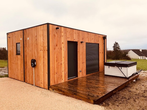 A wooden cabin with a door, a window, and a small deck. - Lenny's chalet-Spa-wifi-electric terminal-near Beauval (Luçay-le-Mâle)