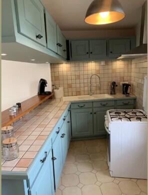 A kitchen with teal cabinets, a gas stove, and a tiled backsplash. - Maison proche du lac-4 pers-wifi-cour (Châteauroux)