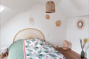 A bedroom with a bed, a hanging light, wall decorations, and a small table.