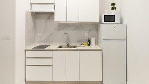 A modern kitchen with white cabinets, a stainless steel sink, a microwave, and a refrigerator.