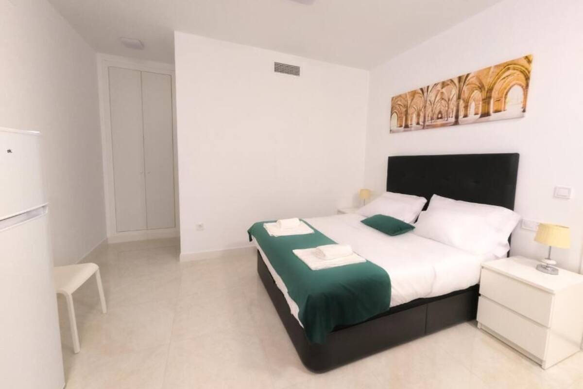 A bedroom with a bed, bedside table, and a wall-mounted artwork.