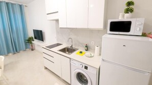 A compact kitchen with a washing machine, a microwave, and a sink.