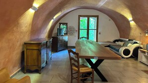 Una habitación en el ático con una mesa de comedor, sillas, un sofá y una televisión.