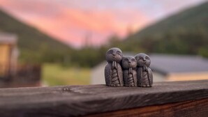 Una barandilla de madera con tres pequeñas figuras de piedra.