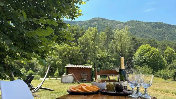 Un espacio exterior para comer con una mesa, sillas y una botella de champán.