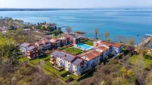 Complejo residencial con piscina, rodeado de vegetación y vistas a una amplia extensión de agua.