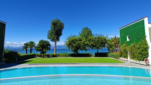 Una piscina con vista despejada al mar y montañas al fondo.