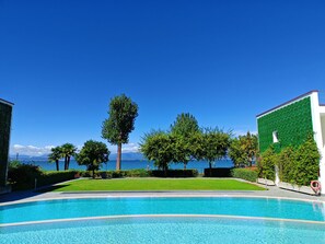 A swimming pool with a clear view of the sea and mountains in the background.