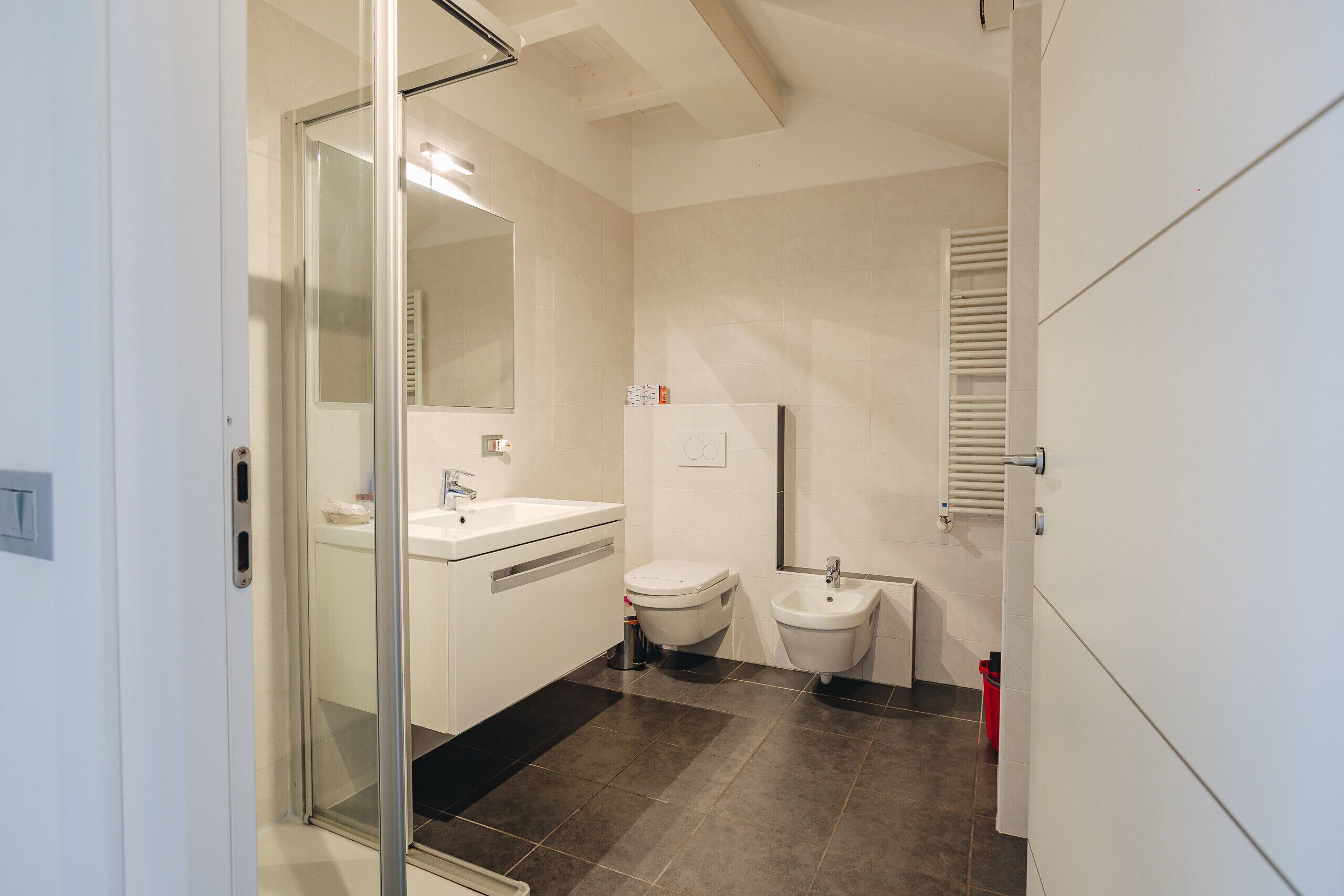 Een moderne badkamer met een glazen douchecabine, toilet, bidet en wastafel.