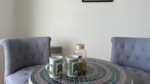 A round table with two white mugs featuring floral designs, a small glass jar with a cork lid, and a framed black and white photograph on the wall. - Seaside Studio in Notre-Dame-de-Monts - Pets allowed, Parking (Notre-Dame-de-Monts)
