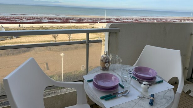 A balcony with a table set for two, overlooking a beach with red vegetation and a clear sky. - Seaside Studio in Notre-Dame-de-Monts - Pets allowed, Parking (Notre-Dame-de-Monts)