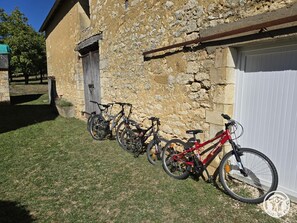 A stone building with a garage door, a grassy area, and bicycles parked outside.