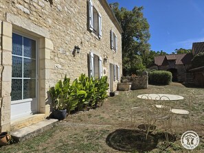 A stone building with a garden, outdoor seating, and a clear sky.