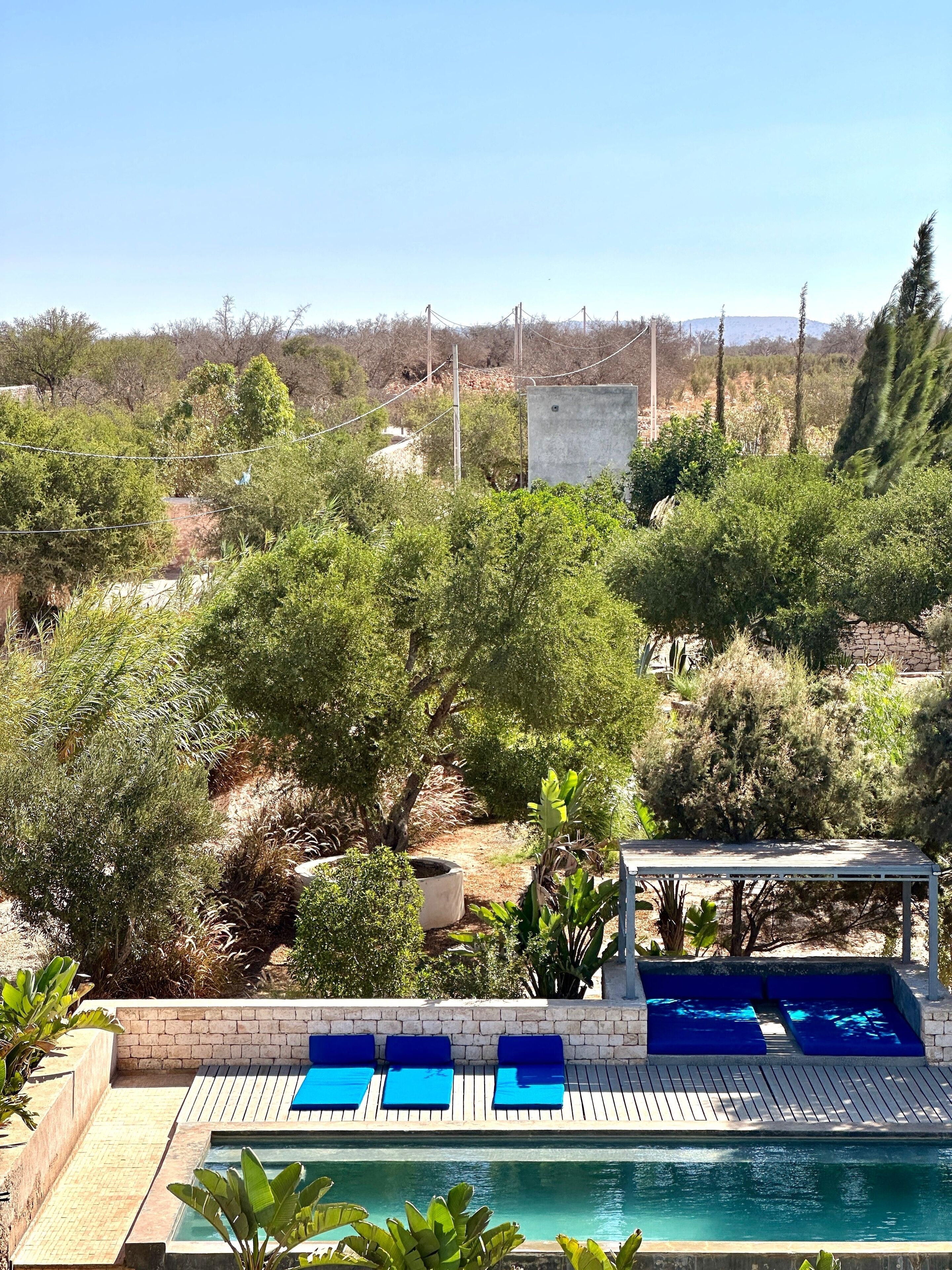 En swimmingpool med blå solstolar och en pergola.