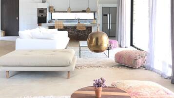 Una sala de estar moderna con sofá, reposapiés y una mesa redonda de madera con planta en maceta.