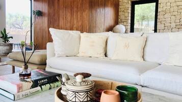 Una sala moderna con un sofá blanco, paneles de madera y una pared de piedra.
