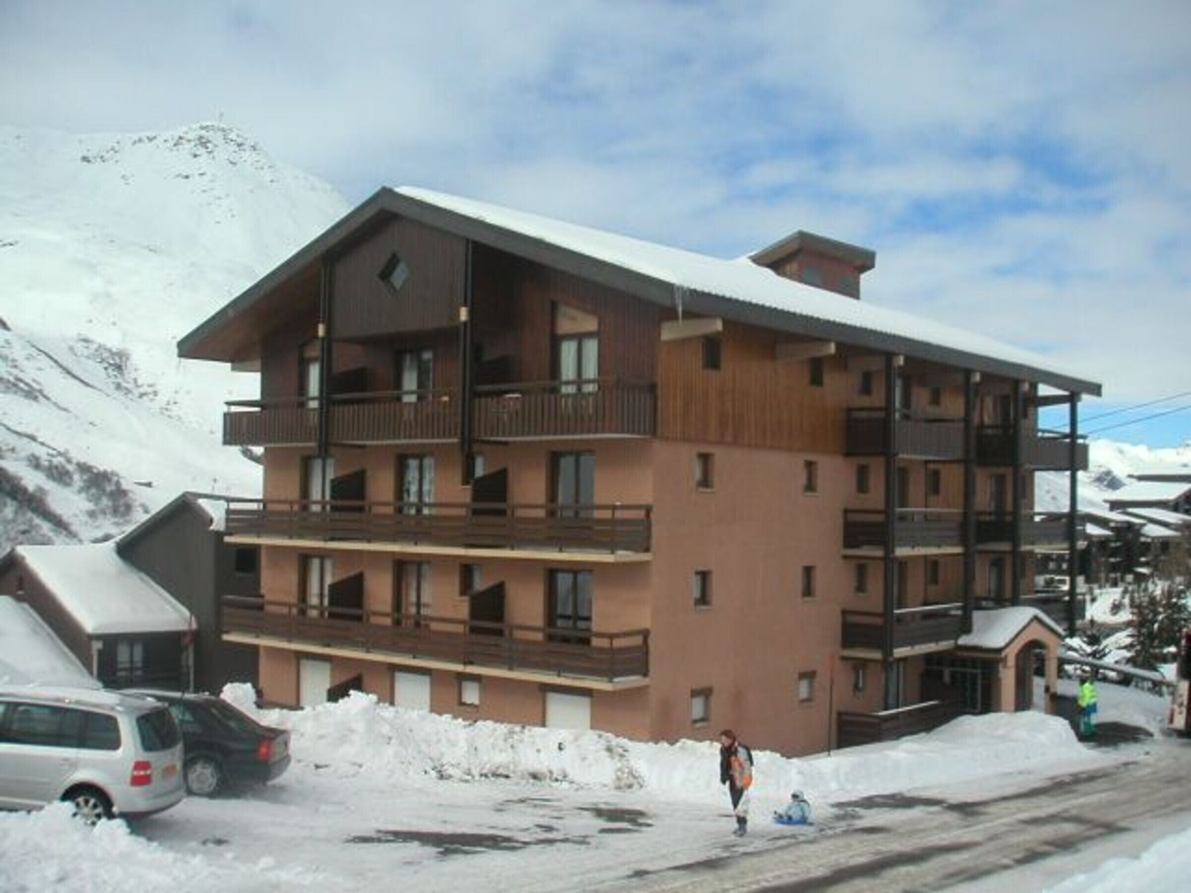 Un immeuble à plusieurs étages doté de balcons, entouré de montagnes enneigées.