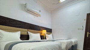 A hotel room with a large bed, a bedside table with a lamp, an air conditioning unit, and a patterned carpet. - Eqamh Etlala Quba- إقامة إطلالة قباء (Madinah)