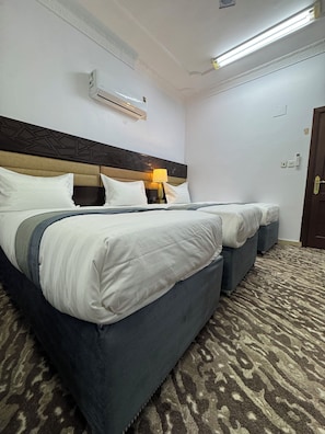 A hotel room with a large bed, a bedside table with a lamp, an air conditioning unit, and a patterned carpet. - Eqamh Etlala Quba- إقامة إطلالة قباء (Madinah)