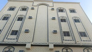 A tall building with a symmetrical facade, featuring a central arched window and decorative patterns around the windows and corners. - Eqamh Etlala Quba- إقامة إطلالة قباء (Madinah)