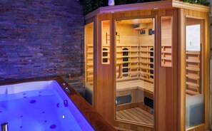 A sauna with a wooden exterior and a glass door, a wooden bench inside, and a stone wall in the background. - ✨Romantic Night with Balneotherapy & Sauna | Optional Erotic Escape Game ✨   (Carcassonne)