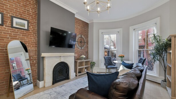 A living room with a fireplace, a large mirror, a leather sofa, and a television mounted on the wall. - 2 Bed Luxury Condo in South End near Restaurant Row, (Boston)